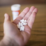 A hand holding a large amount of cyclobenzaprine pills.