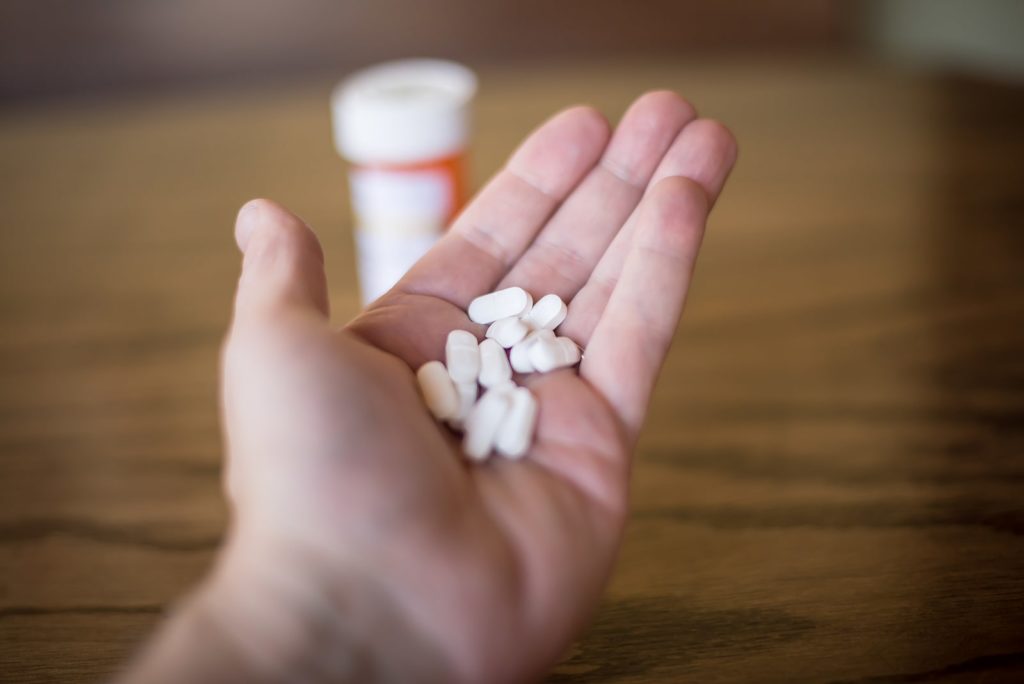 A man holds a handful of opioids to use as mood stabilizers.