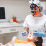 A woman getting her teeth checked and cleaned by a dental assistant.