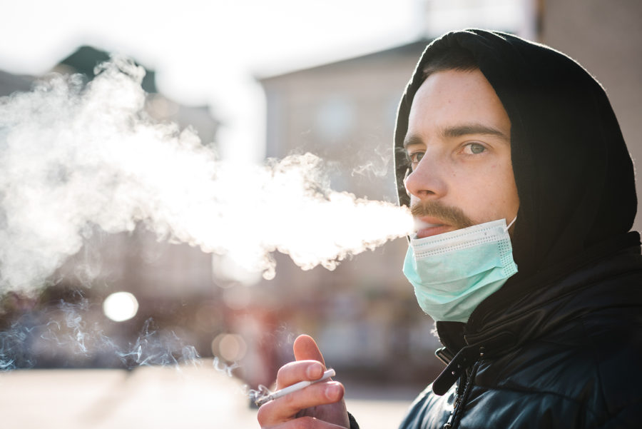 A man smoking a cigarette outside.