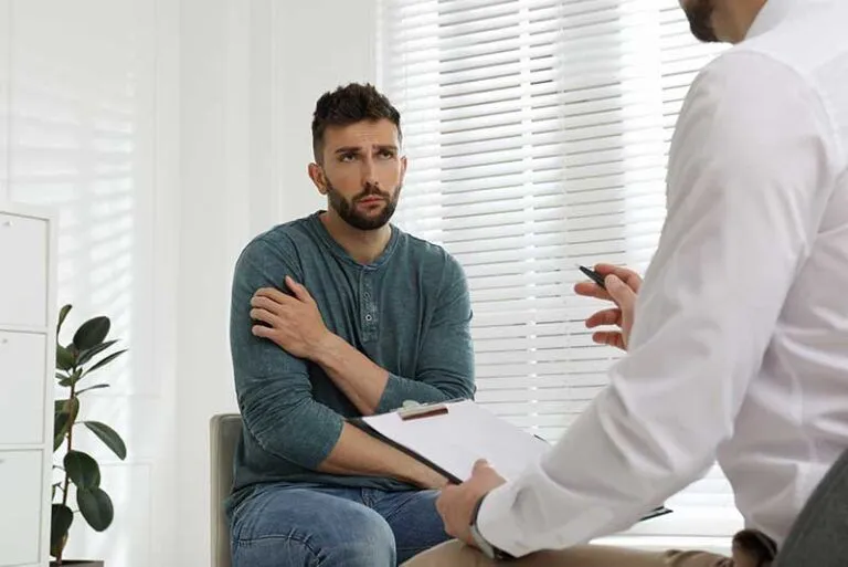 Man sits and listens to doctor at an ecstasy addiction treatment program
